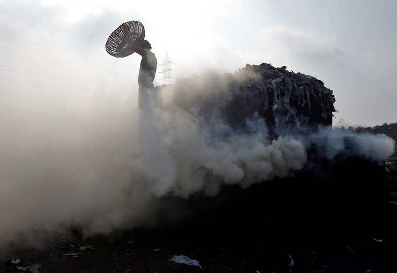 A labourer carries an empty basket after putting leather scrap on a burning oven for making fertilizers at a factory on the outskirts of  Kolkata