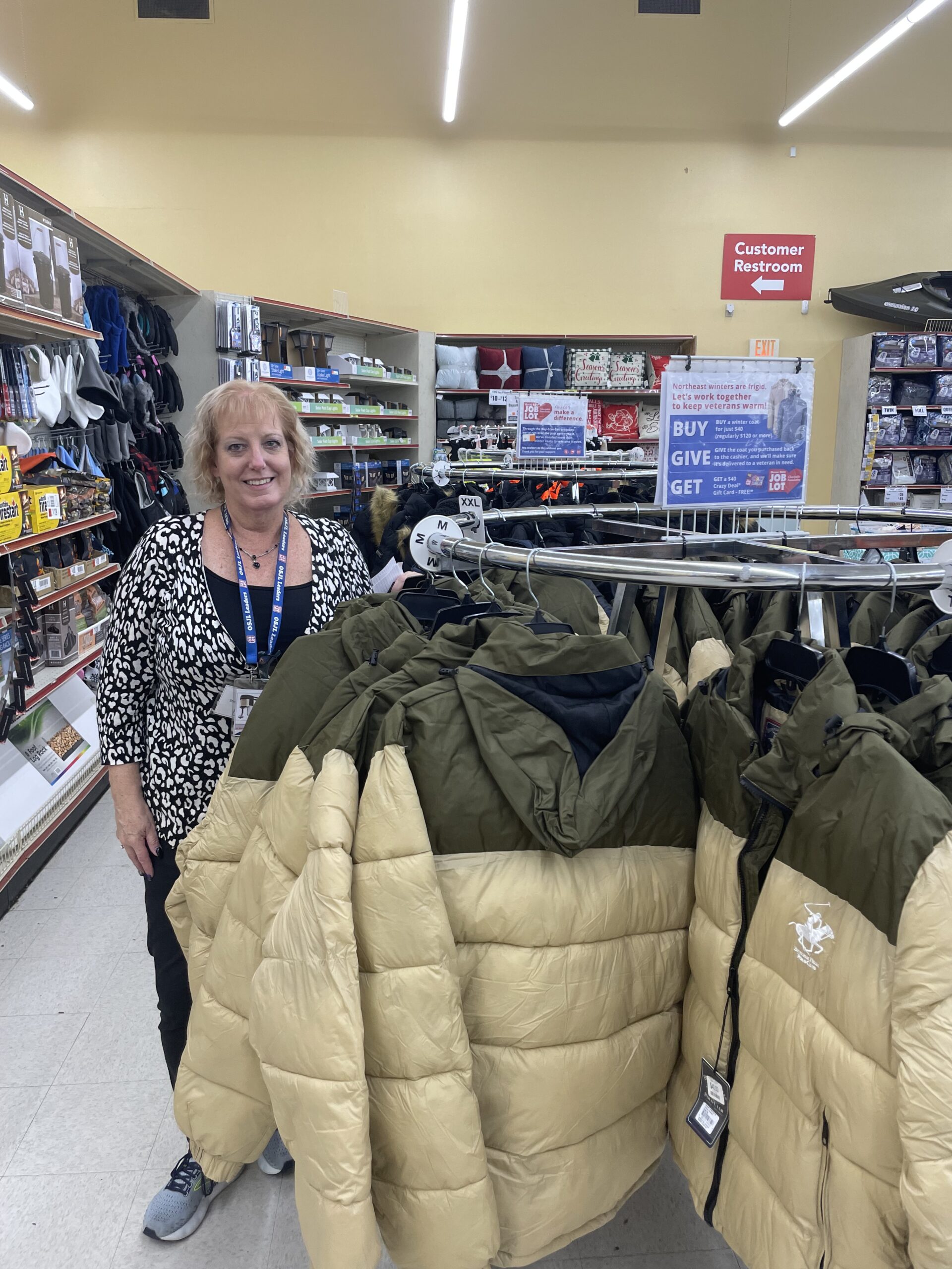 Nanuet Store Team Lead Kim Roland in front of Buy, Give, Get coats.